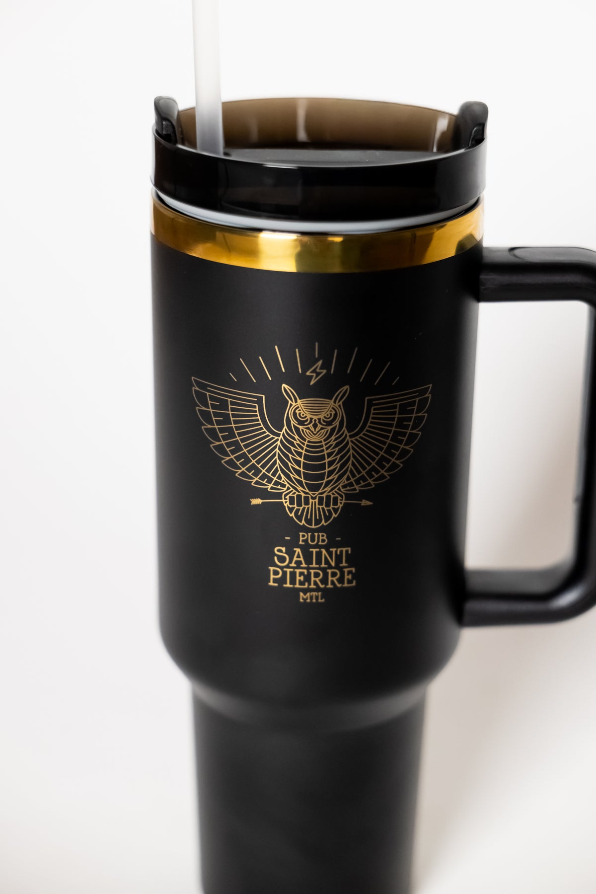 Close-up of the gold owl crest on the Pub Saint Pierre travel tumbler