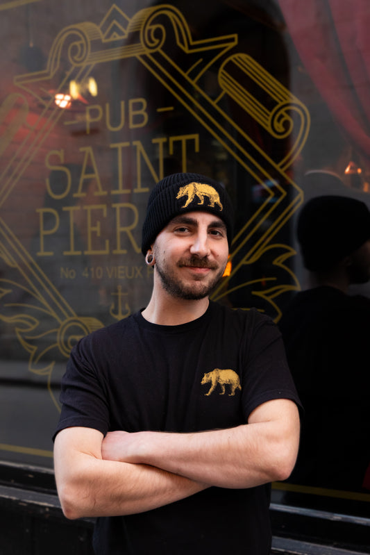 Wearing the black Pub Saint Pierre toque outside the pub's gold window sign, gold bear on the cuff