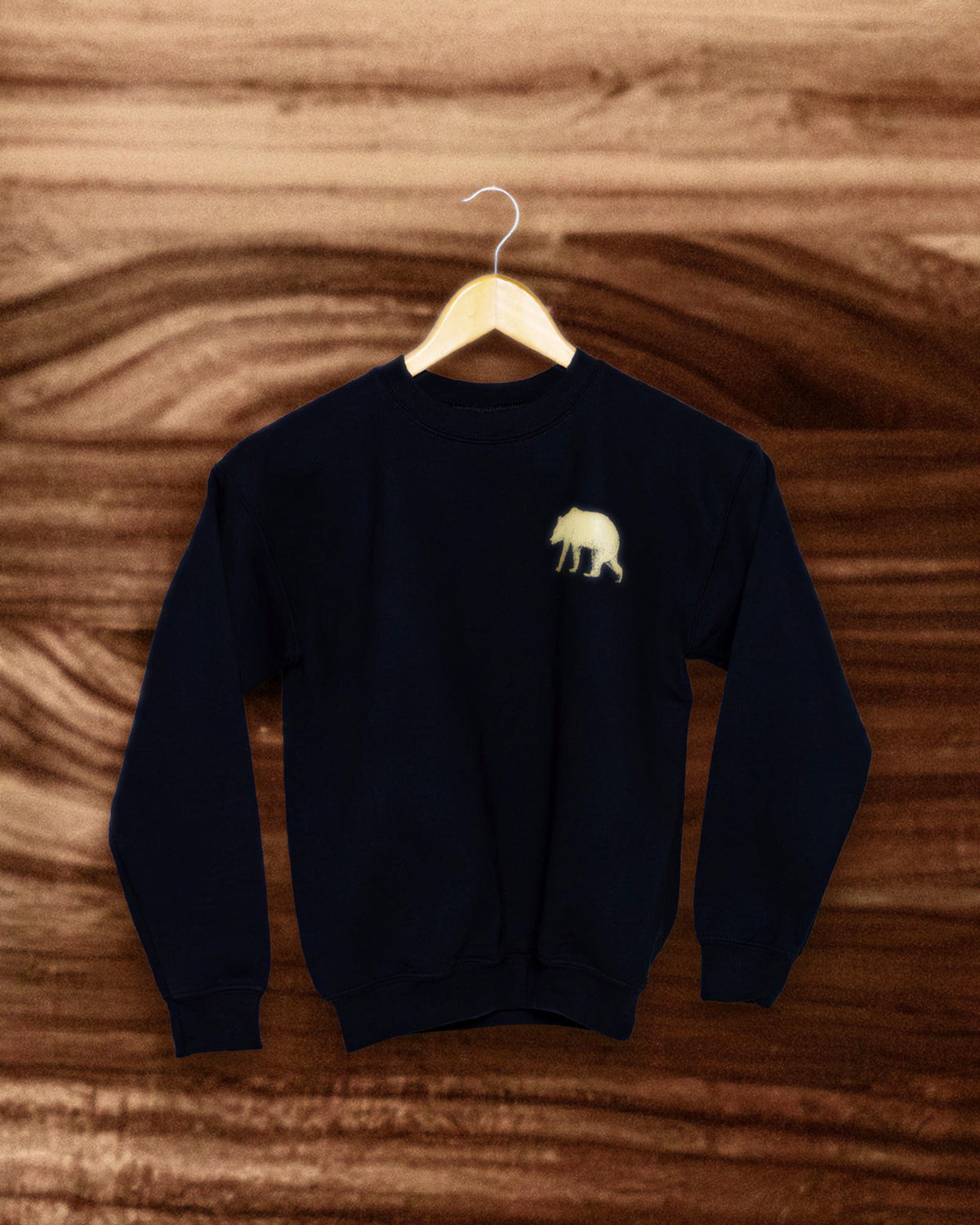 Kids Pub Saint Pierre crewneck on a wooden hanger against a walnut background, gold bear at the chest
