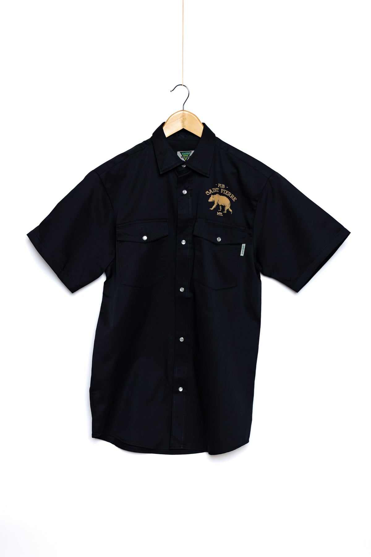 Front of the black Pub Saint Pierre work shirt on a white background, gold bear on the chest pocket